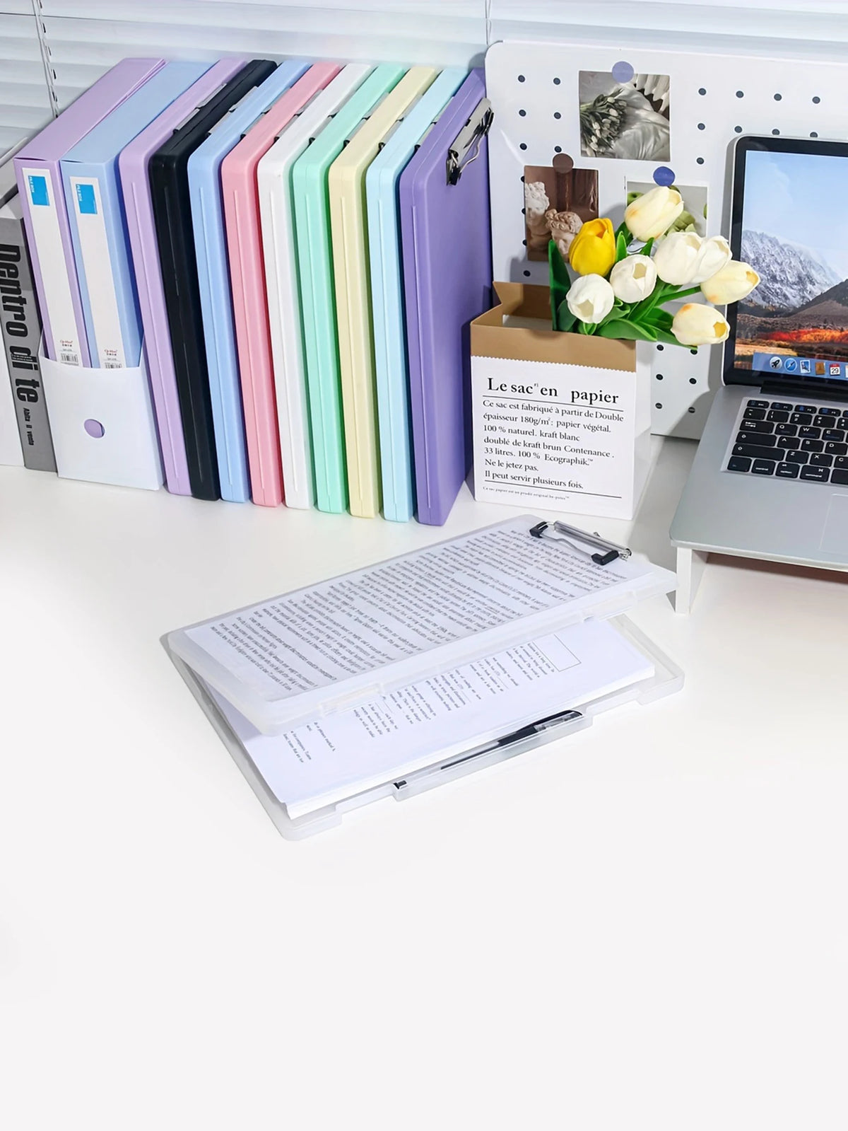 A set of colorful A4 document and photo storage file boxes lined up next to a laptop and a box of flowers.