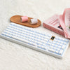 Weiße mechanische Tastatur mit rosa Tastenkappen neben dekorhaftem rosa Brot und gerollten Stofftastenkappen.