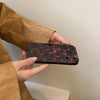 A hand wearing a brown jacket holds an Amber retro shockproof phone case for iPhone.