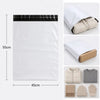 A white self-adhesive courier mailer bag is shown next to a stack of beige knitted gloves and a gray knitted hat.