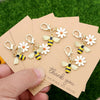 A set of five cute ladybug and daisy keychains is shown on thank you cards against a green background.