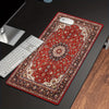 A vintage Persian rug designed as a gaming mouse pad with a non-slip rubber base placed on a dark desk.