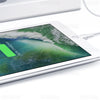 A tablet displaying a green battery icon, connected to a white charging cable.