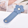 A light blue leather flower cable organizer with a silver button and a small metal stud, shown against a soft background.