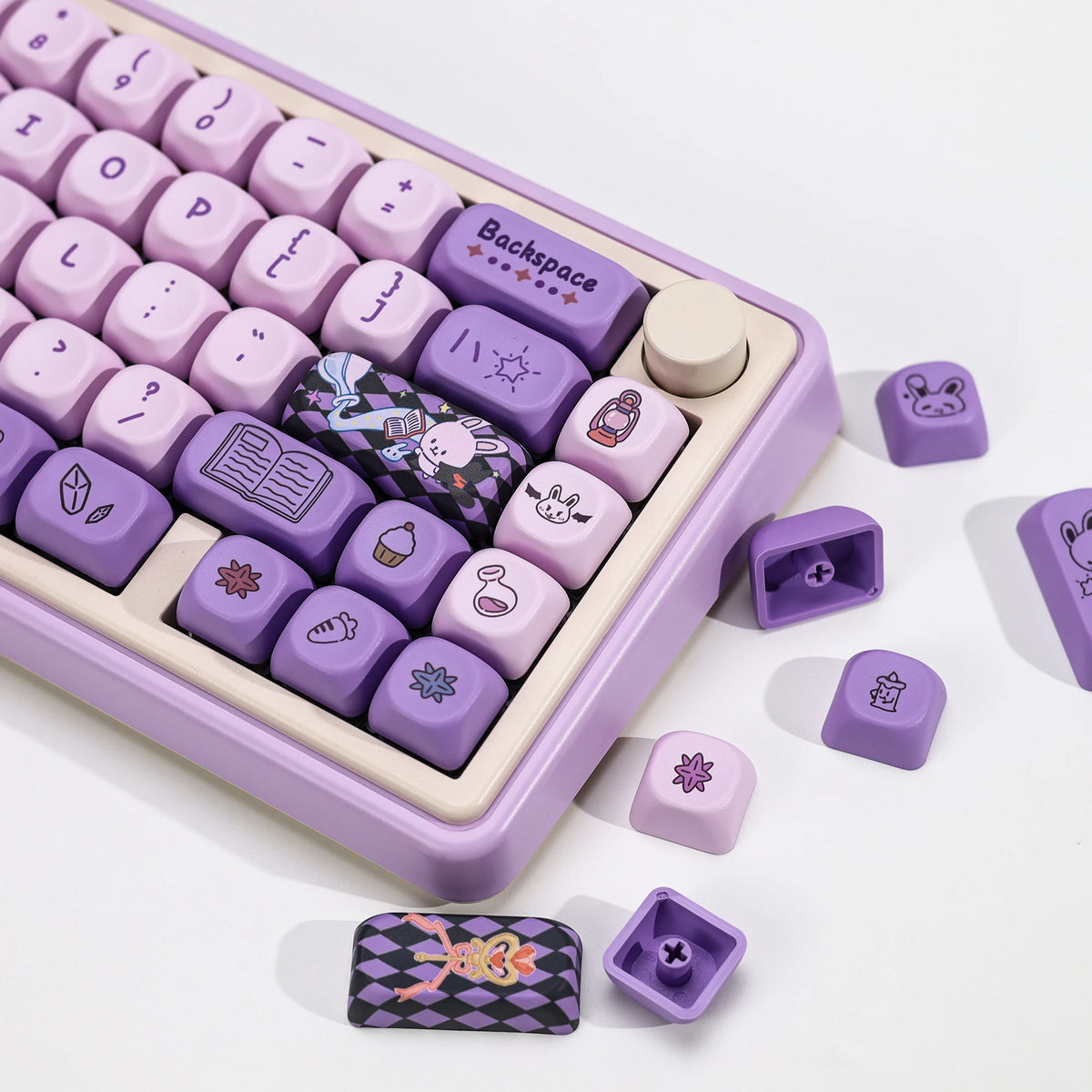 A purple PBT keycap set featuring magic bunny designs and a Backspace key, displayed in its storage case.