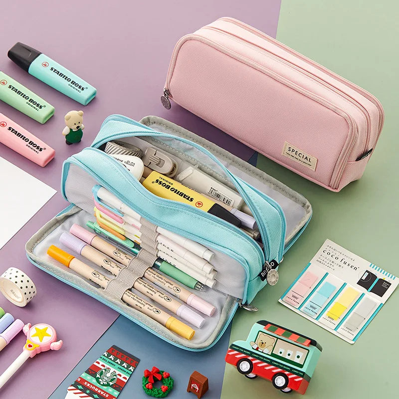 A pink pencil pouch is shown open, filled with various colored pencils and art supplies on a green background.