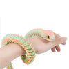 A hand is holding an articulated 3D printed snake figurine with pink and green scales.