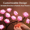 Hands are adjusting bendable branches and realistic rose flowers on a dark tree light.