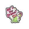 An enamel pin featuring a sarcastic green frog holding a pink heart and text that reads Am I the Drama