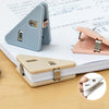 A close-up of a light gray triangle folder clip and a pink folder clip resting on a stack of white papers.