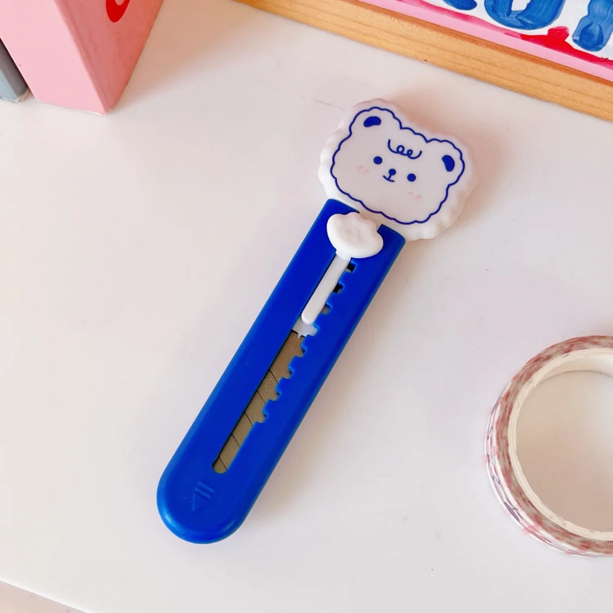 A blue mini cutter shaped like a cat paw with a white bear face is shown on a white surface.