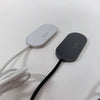 A gray magnetic wireless charging adapter with a black cable and a dark gray charging pad is shown on a white surface.
