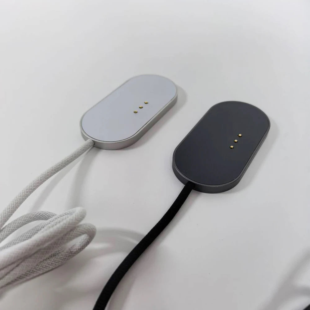 A gray magnetic wireless charging adapter with a black cable and a dark gray charging pad is shown on a white surface.