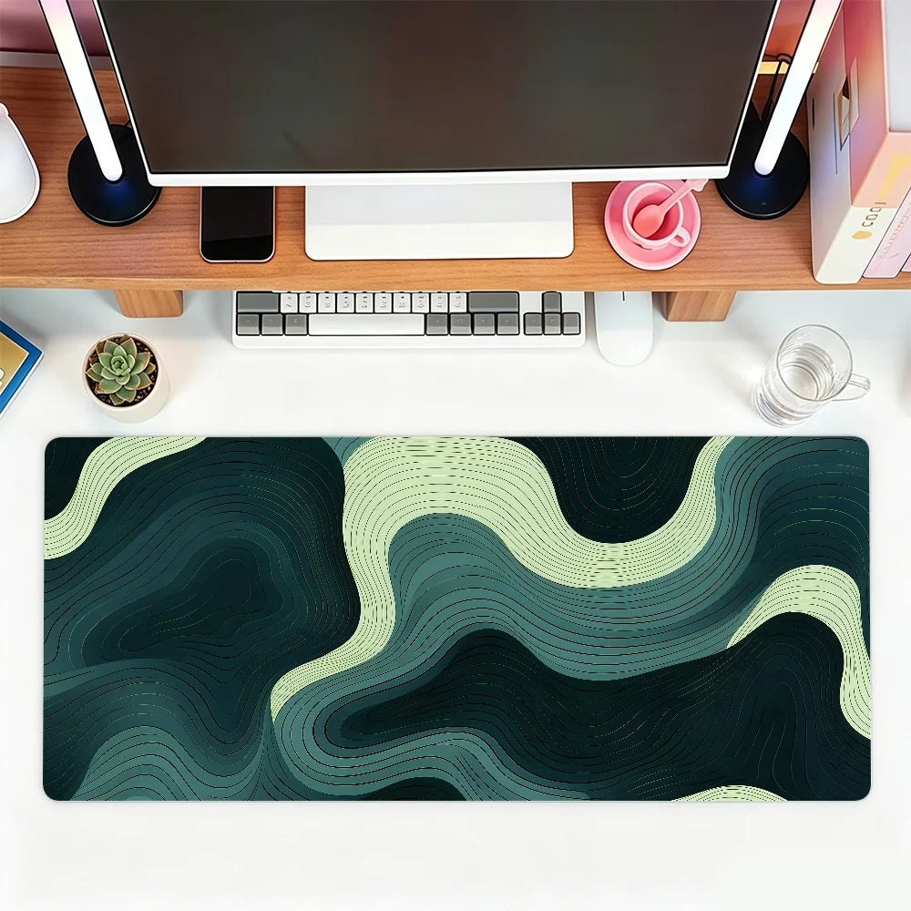 A dark green and beige abstract wave mouse pad placed on a wooden desk with a laptop and peripherals.