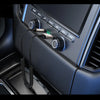 A close-up view of a car stereo unit with various buttons and a connected audio adapter cable.