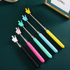 A set of colorful retractable hand pointer sticks with yellow, light blue, pink, and teal tips on a dark green surface.