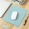 A light blue mouse pad with a white wireless mouse and a black pen are displayed on a wooden surface.