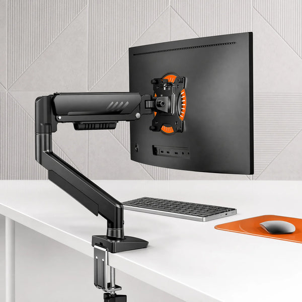 A black fully adjustable monitor arm is mounted on a desk, positioned next to a computer monitor.