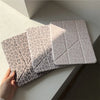 A stack of clear and patterned leopard print leather cases for an iPad displayed on a white surface.