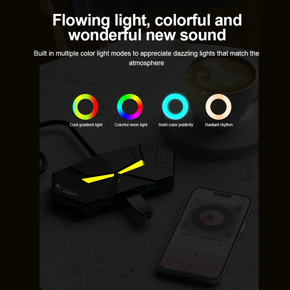 A black USB 3.0 multi-port hub with a yellow light is shown next to a smartphone and a cup of coffee.