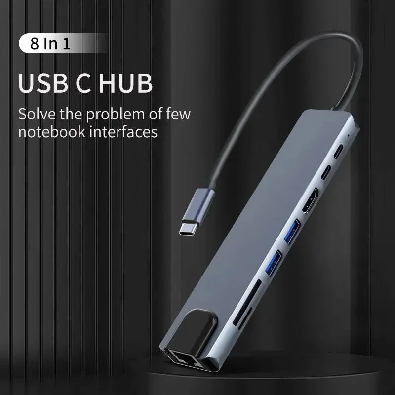 A silver 8 in 1 USB C Hub is shown connected by a cable, positioned against a dark background.