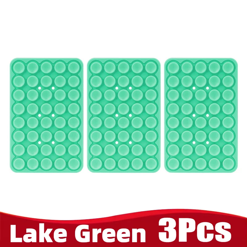 Three light green silicone suction cup phone holders arranged in a row.
