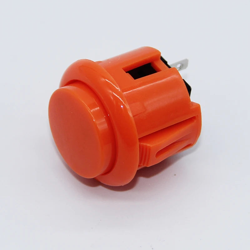 An orange arcade push button game switch with a black component and metal clip.