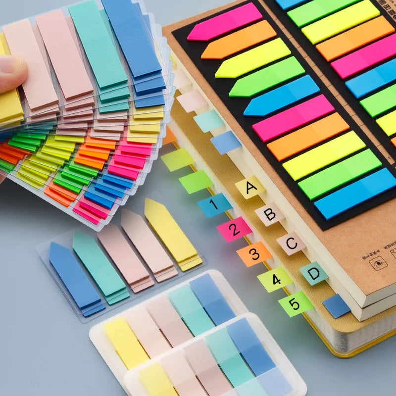 A colorful set of fluorescent PET sticky notes with index tabs arranged in a grid on a wooden surface.
