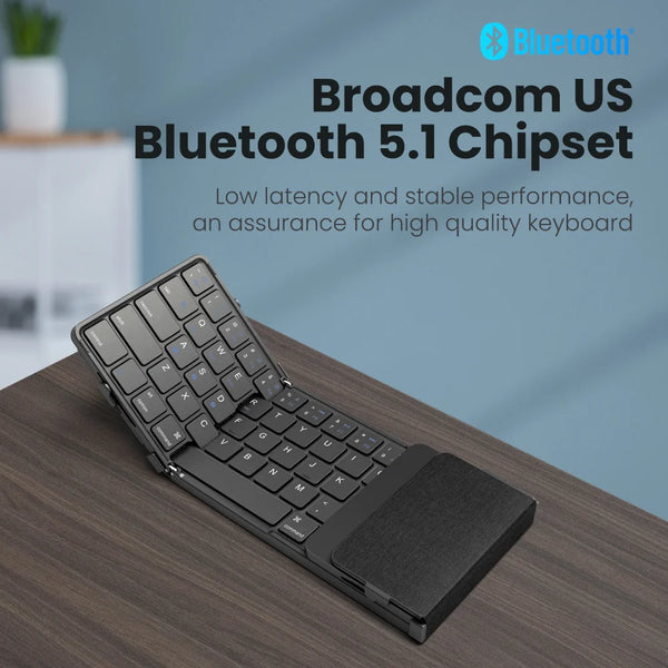 A black foldable Bluetooth keyboard with a touchpad is shown on a wooden desk.