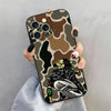 A phone case featuring a camouflage pattern with eyes and a hunting dog design.