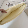 A pale yellow padded laptop sleeve case with a zipper and soft lining is shown diagonally.