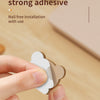 A hand is applying a piece of a cartoon desk cable organizer to a surface.