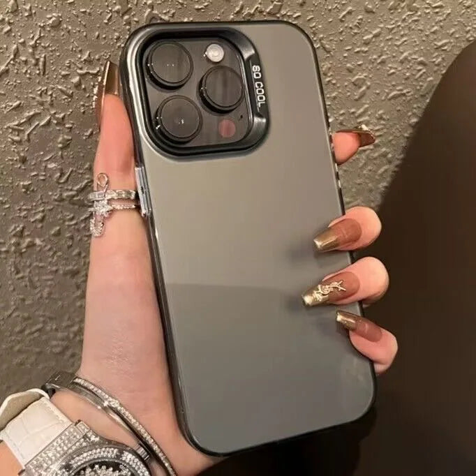 A hand holds a matte gray iPhone with a clear case, featuring gold jewelry and nails.