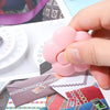 A hand holds a pink floral design letter opener and paper cutter next to various colored papers.