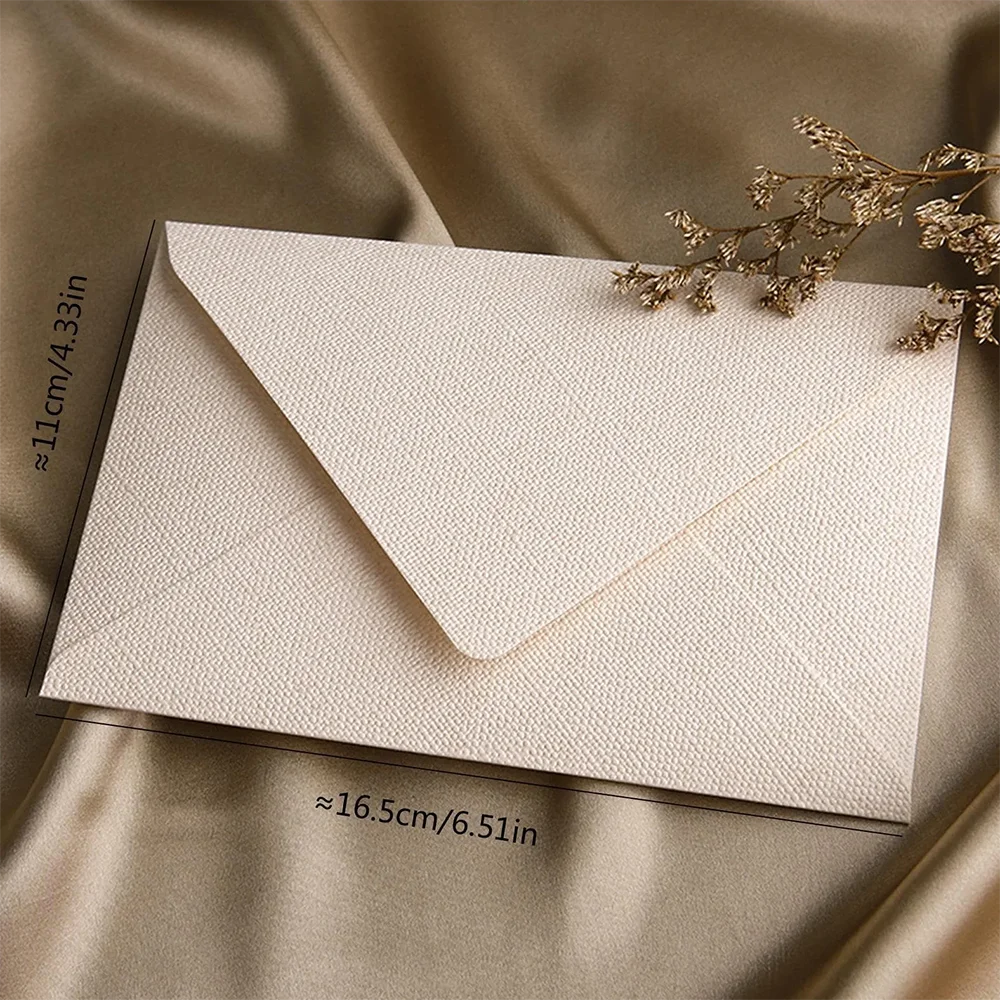 Beige Retro Leinen-Umschlag aus braunem Papier liegt auf seidigem braunem Stoff.
