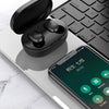 Un par de auriculares inalámbricos Bluetooth negros descansando sobre un teclado de portátil con un gráfico de reducción de r