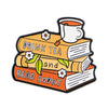 An enamel lapel pin depicting a stack of books with a teacup on top.
