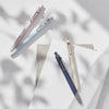 Three precision gel pens in pink and blue are angled against a light background with soft shadows.