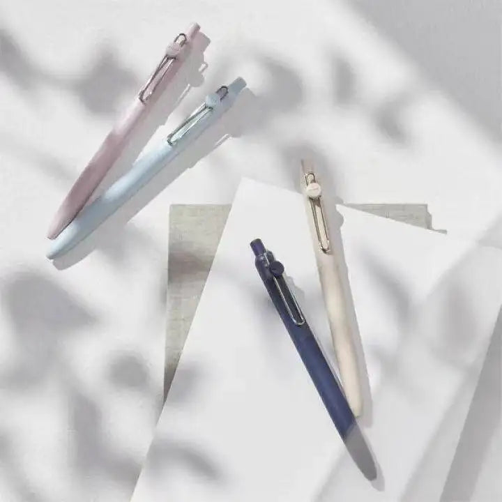 Three precision gel pens in pink and blue are angled against a light background with soft shadows.