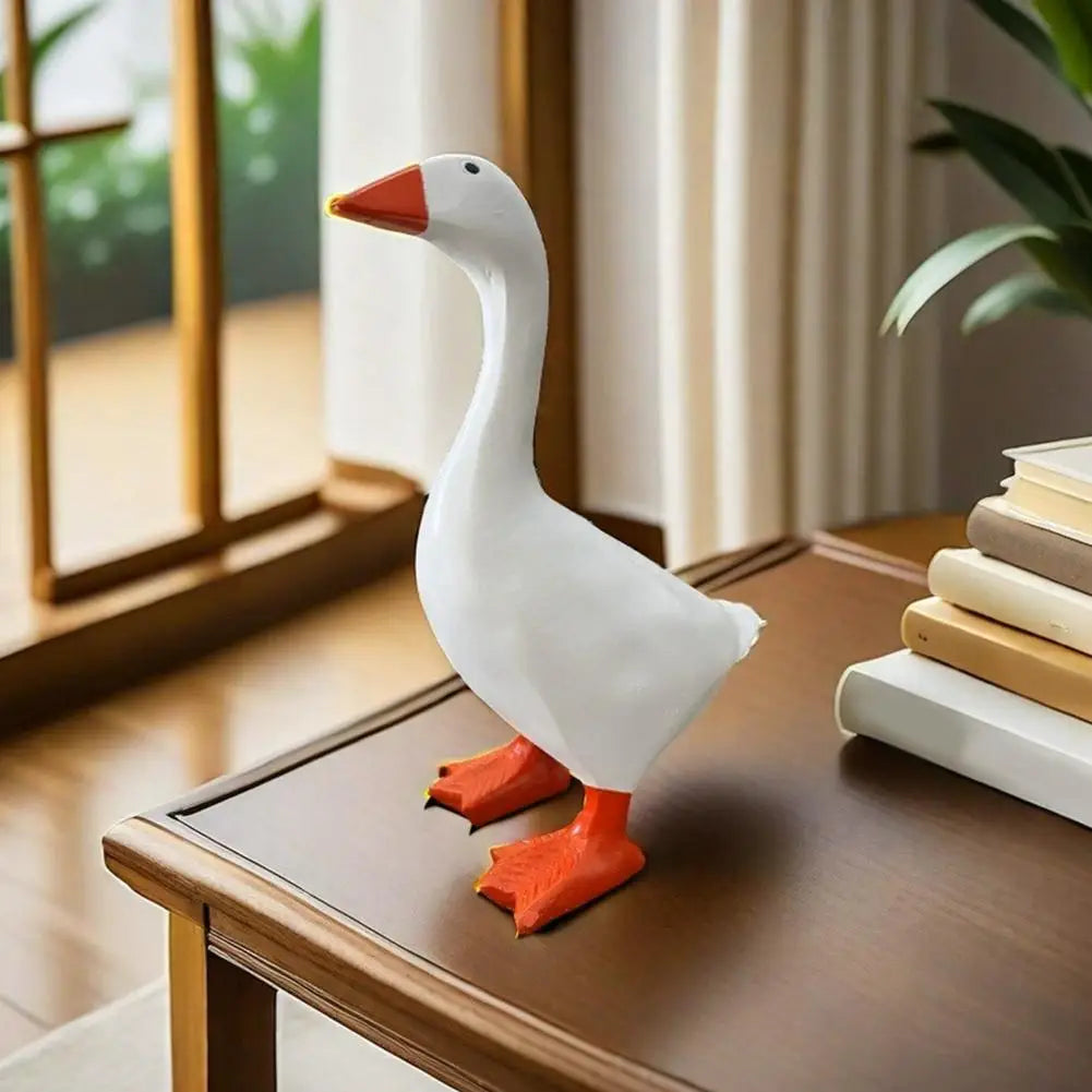 A white resin magnetic duck key holder with an orange beak and feet sitting on a wooden desk.