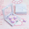 A clear plastic case holds purple cat paw and pink heart keycaps for MX switches on a pink background.