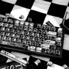 A close-up view of a black mechanical keyboard featuring comic-style PBT keycaps in black and white.