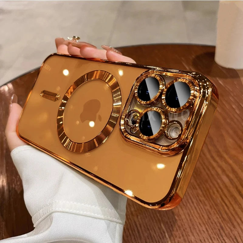 A hand holds a gold-plated magnetic clear case for an iPhone on a wooden surface.