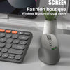 A gray wireless mouse with a multifunction screen is shown next to a laptop and a potted plant.