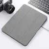 A gray retro marbling skin for an iPad Pro placed next to a laptop and camera lens.