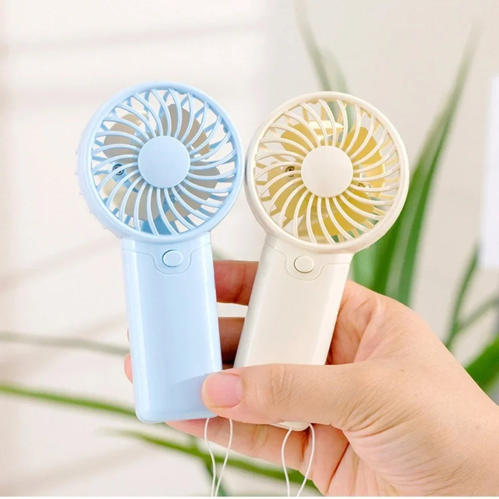 A hand holds two portable rechargeable mini handheld fans, one blue and one white.