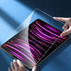A hand is gently fitting a clear tempered glass screen protector onto an iPad screen.