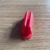 A red silicone self-adhesive pen holder with two prongs resting on a wooden surface.