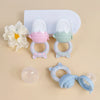 A silicone fruit and vegetable feeder set for babies and toddlers, featuring two colored feeding cups on a white tray.