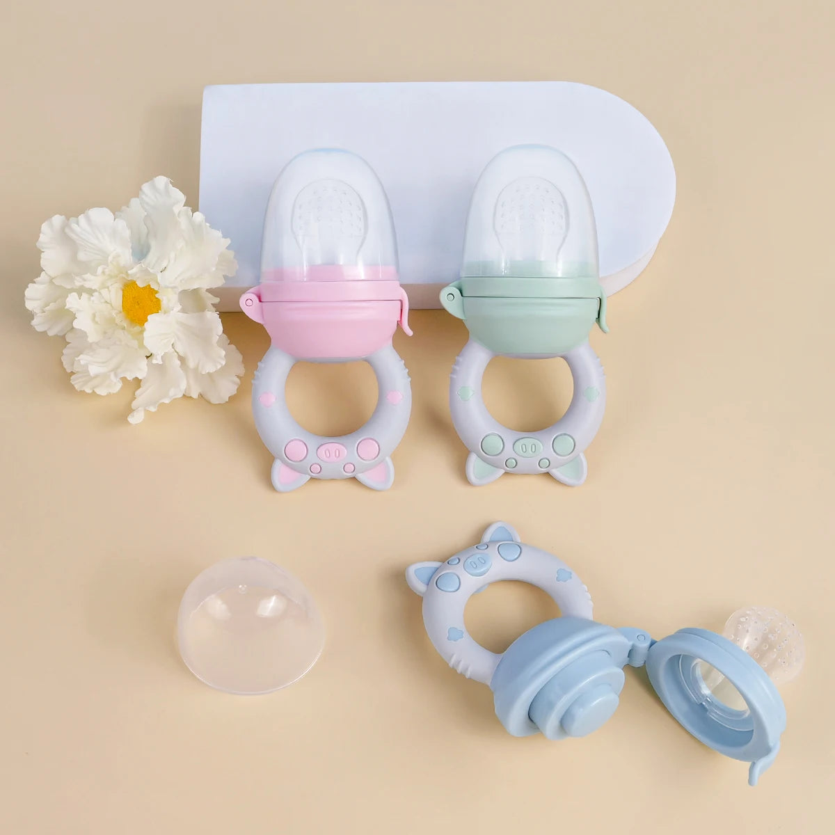 A silicone fruit and vegetable feeder set for babies and toddlers, featuring two colored feeding cups on a white tray.